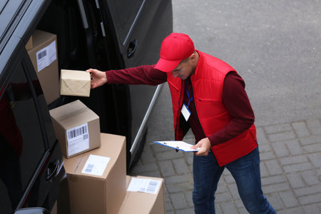 Courier checking amount of parcels in delivery van outdoorsの写真素材