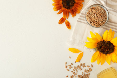 Sunflowers, oil and seeds on white table, flat lay. Space for textの写真素材