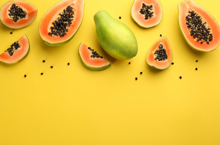 Fresh ripe papaya fruits on yellow background, flat lay. Space for textの写真素材