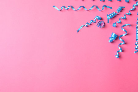 Light blue serpentine streamers on pink background, flat lay. Space for textの写真素材