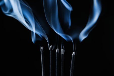 Incense sticks smoldering on black background, closeupの写真素材