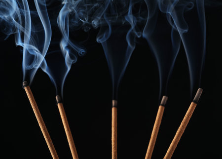 Incense sticks smoldering on black background, closeupの写真素材