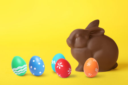 Chocolate bunny and painted Easter eggs on yellow backgroundの写真素材
