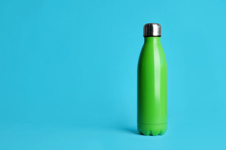 Stylish thermo bottle on light blue background, space for textの写真素材
