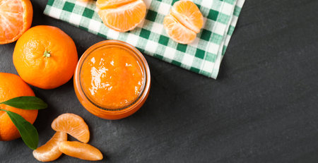 Flat lay composition with tasty tangerine jam on dark table. Space for textの写真素材