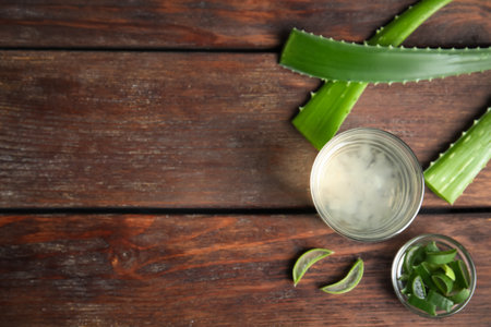 Fresh aloe drink in glass and leaves on wooden table, flat lay. Space for textの写真素材