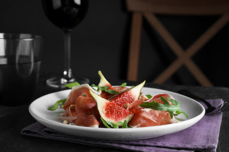 Delicious figs and proscuitto on black tableの写真素材