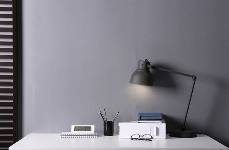 Lamp and different stationery on table in office. Space for textの写真素材