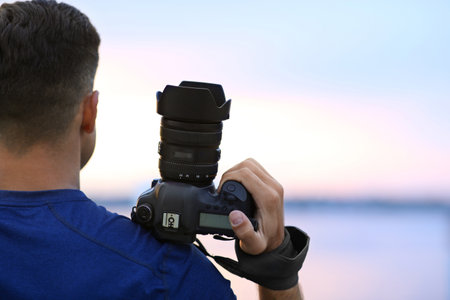 Photographer with professional camera near river at sunset, closeupの写真素材