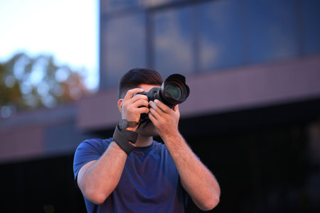 Photographer taking picture with professional camera on city street in the evening