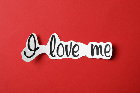Piece of paper with handwritten phrase I Love Me on red background, top viewの写真素材