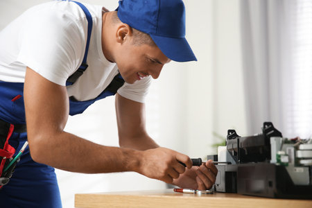 Repairman with screwdriver fixing modern printer in officeの写真素材