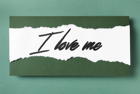 Paper with handwritten phrase I Love Me on green background, top viewの写真素材