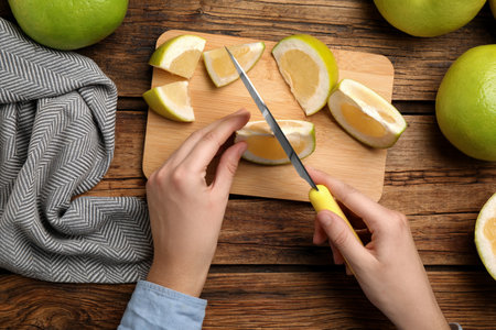 Woman cutting sweetie fruit at wooden table, top viewの写真素材