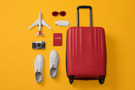 Flat lay composition with suitcase and travel accessories on yellow background. Summer vacationの写真素材