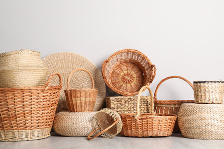 Many different wicker baskets made of natural material on floor near light wallの写真素材