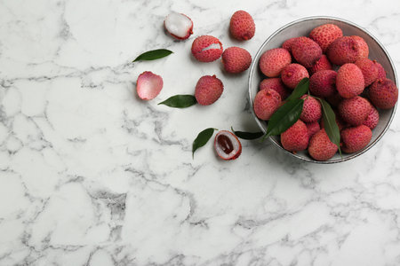 Fresh ripe lychee fruits in bowl on white marble table, flat lay. Space for textの写真素材