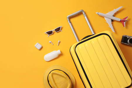 Flat lay composition with suitcase and travel accessories on yellow background. Summer vacationの写真素材