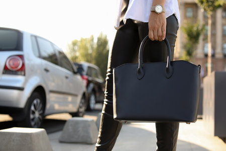 Young woman with stylish black bag on city street, closeupの写真素材