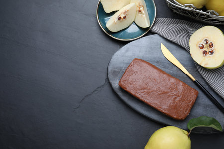 Flat lay composition with delicious quince paste on black table, space for textの写真素材