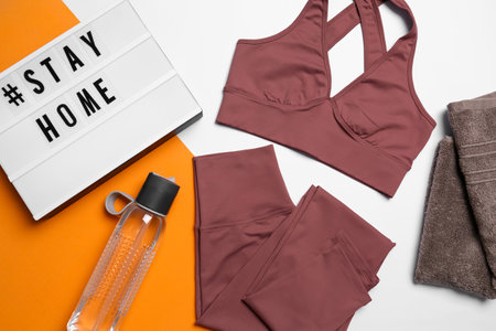 Stylish sportswear, yoga mat and light box with hashtag Stay at Home on white background, flat lay.の写真素材