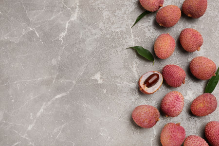 Fresh ripe lychee fruits on grey table, flat lay. Space for textの写真素材