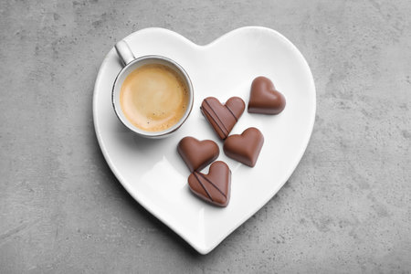 Cup of coffee and chocolate candies on grey table, top view. Valentine's day breakfastの写真素材