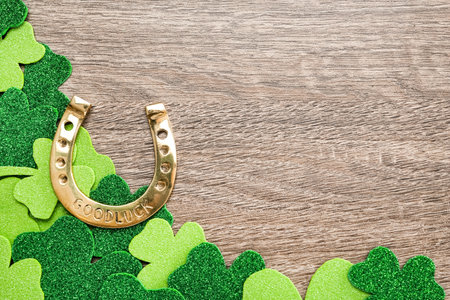 Golden horseshoe and decorative clover leaves on grey wooden table, flat lay with space for text. Saint Patrick's Day celebrationの写真素材