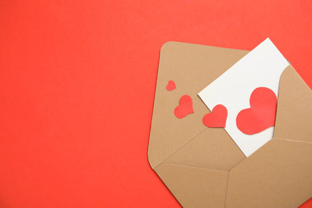 Envelope, card and paper hearts on red background, top view with space for text. Love letterの写真素材
