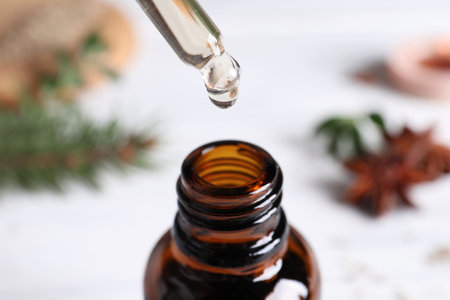 Dropping anise essential oil from pipette into bottle on table, closeupの写真素材