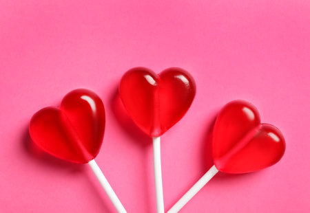 Sweet heart shaped lollipops on pink background, flat lay. Valentine's day celebrationの写真素材