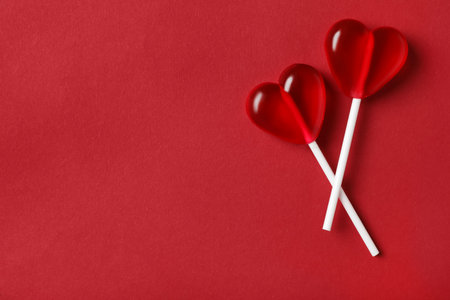 Sweet heart shaped lollipops on red background, flat lay with space for text. Valentine's day celebrationの写真素材