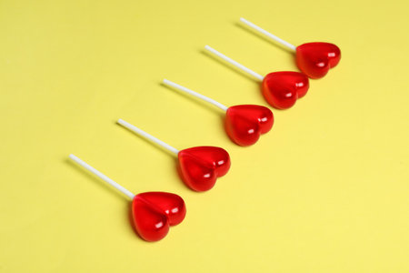 Sweet heart shaped lollipops on yellow background. Valentine's day celebrationの写真素材