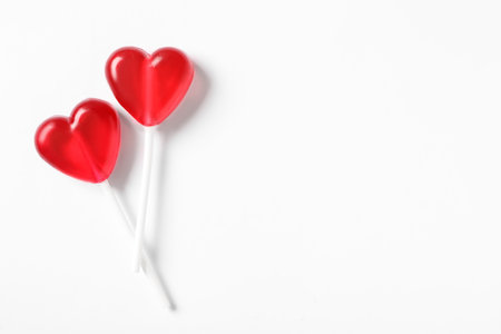 Sweet heart shaped lollipops on white background, flat lay with space for text. Valentine's day celebrationの写真素材