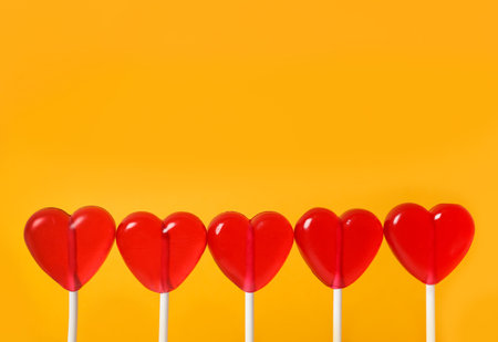 Sweet heart shaped lollipops on orange background, closeup view with space for text. Valentine's day celebrationの写真素材