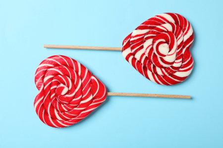 Sweet heart shaped lollipops on light blue background, flat lay. Valentine's day celebrationの写真素材