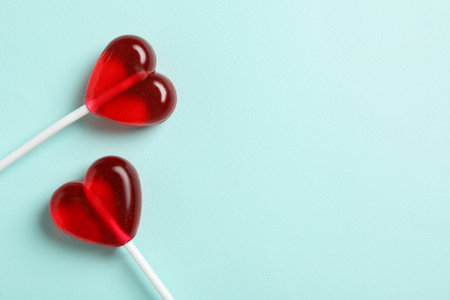 Sweet heart shaped lollipops on light blue background, flat lay with space for text. Valentine's day celebrationの写真素材