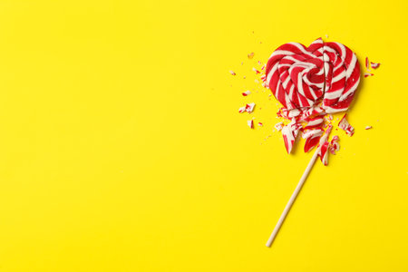 Broken heart shaped lollipop on yellow background, top view with space for text. Relationship problems conceptの写真素材