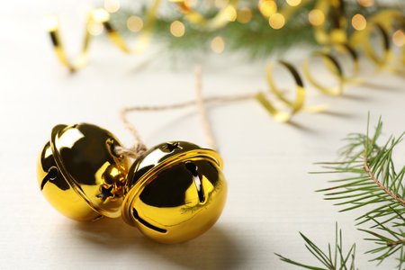 Golden sleigh bells and fir branch on white table, closeupの写真素材