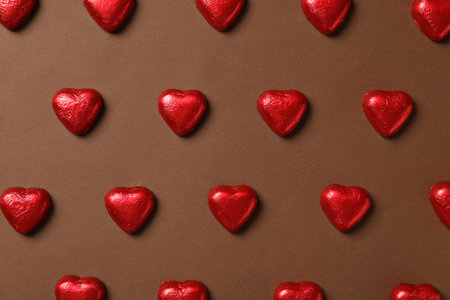 Tasty chocolate heart shaped candies on brown background, flat layの写真素材