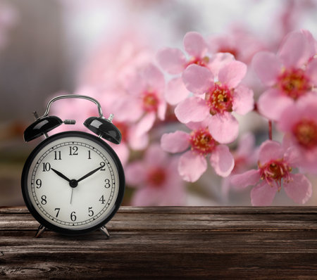 Black alarm clock on wooden table, space for text. Daylight saving time (Spring forward)の写真素材