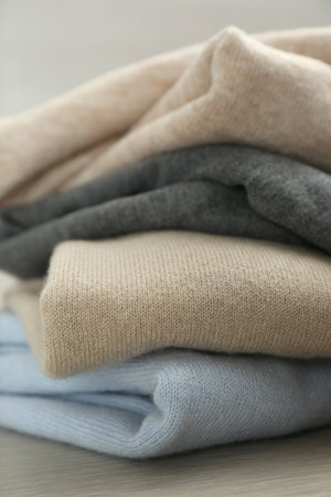 Stack of cashmere clothes on wooden table, closeup