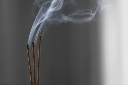 Incense sticks smoldering on blurred background, closeup. Space for textの写真素材