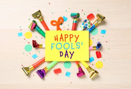 Card with text Happy Fool's Day and party blowers on wooden background, flat layの写真素材