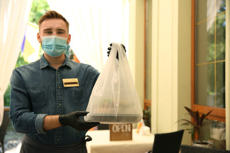Waiter with packed takeout order in restaurant. Food service during coronavirus quarantine