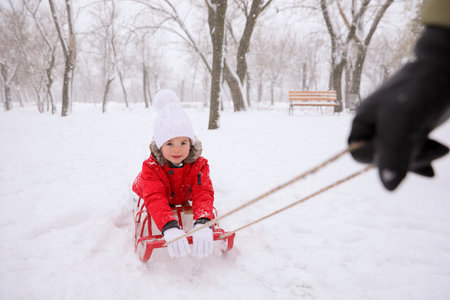 Father sledding his child outside on winter day, closeup. christmas holidaysの写真素材