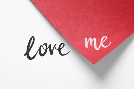 Phrase Love Me written on white and red paperの写真素材