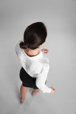 Young businesswoman in elegant suit on gray background, back viewの写真素材