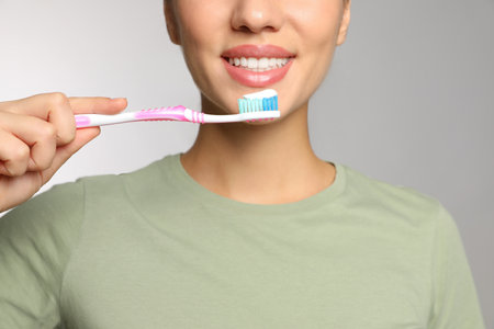 Woman holding toothbrush with paste on light background, closeupの写真素材