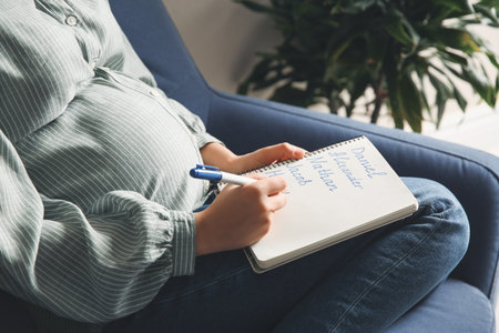 Pregnant woman with baby names list sitting in armchair, closeupの写真素材